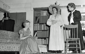 Photo from the play The Curse of the Aching Heart. Three women in period clothing are in the picture. Two are standing and one is sitting.