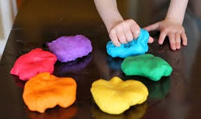 Child's hands playing with rainbow colored playdough