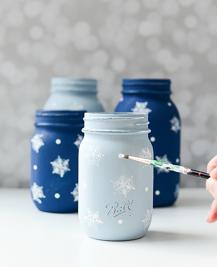 Mason jars painted blue with white snowflakes