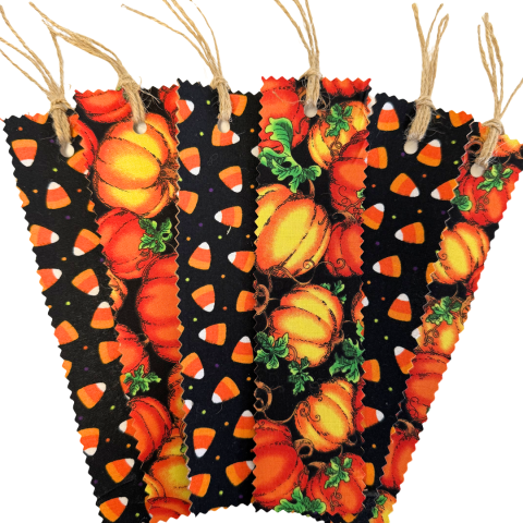 Five bookmarks with pinked edges. They alternate between ones with a black background and candy corn scattered on them and a design with orange pumpkins. There is twine tied at the tops of each bookmark.