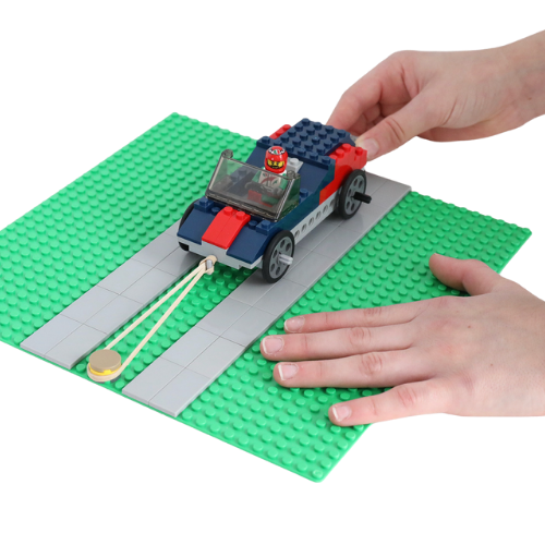 child's hands preparing to launch LEGO car with rubberband 