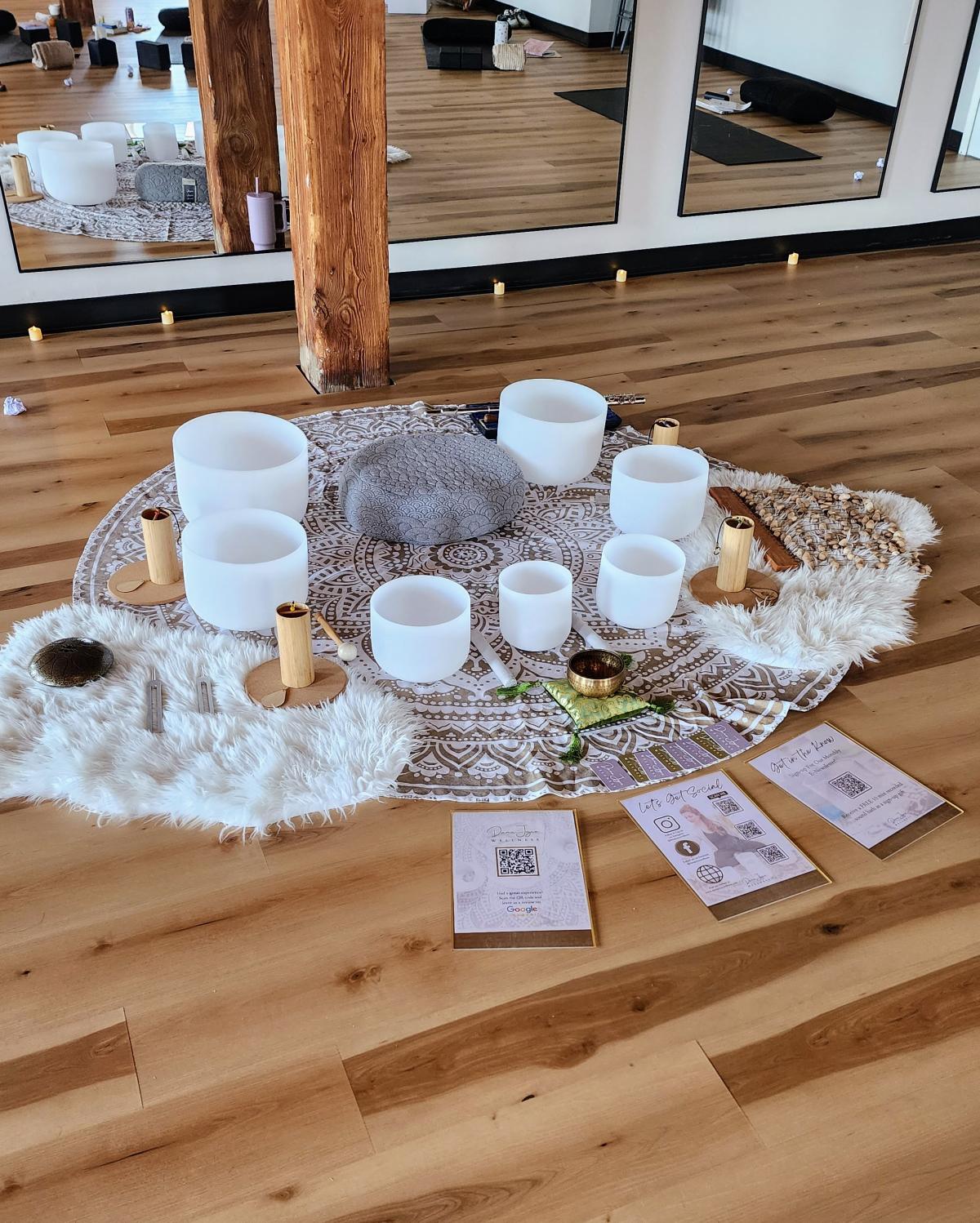White Frosted Singing bowls set up in a half circle around a grey meditation cushion.